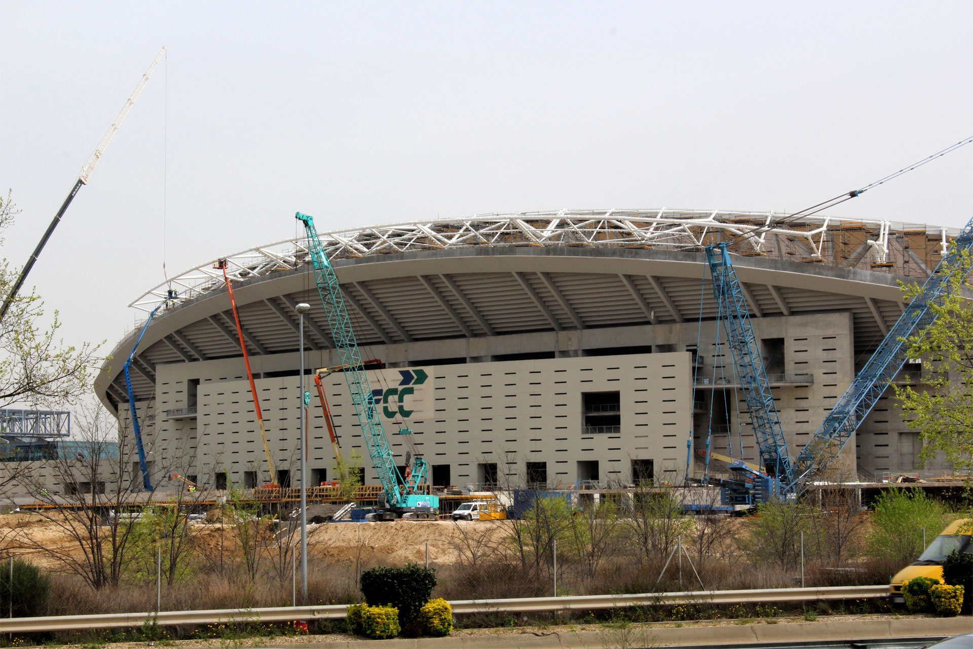 Weitläufige Baustelle eines großen Stadions, das die komplexe Struktur von Kränen und Gerüsten unter einem klaren Himmel präsentiert