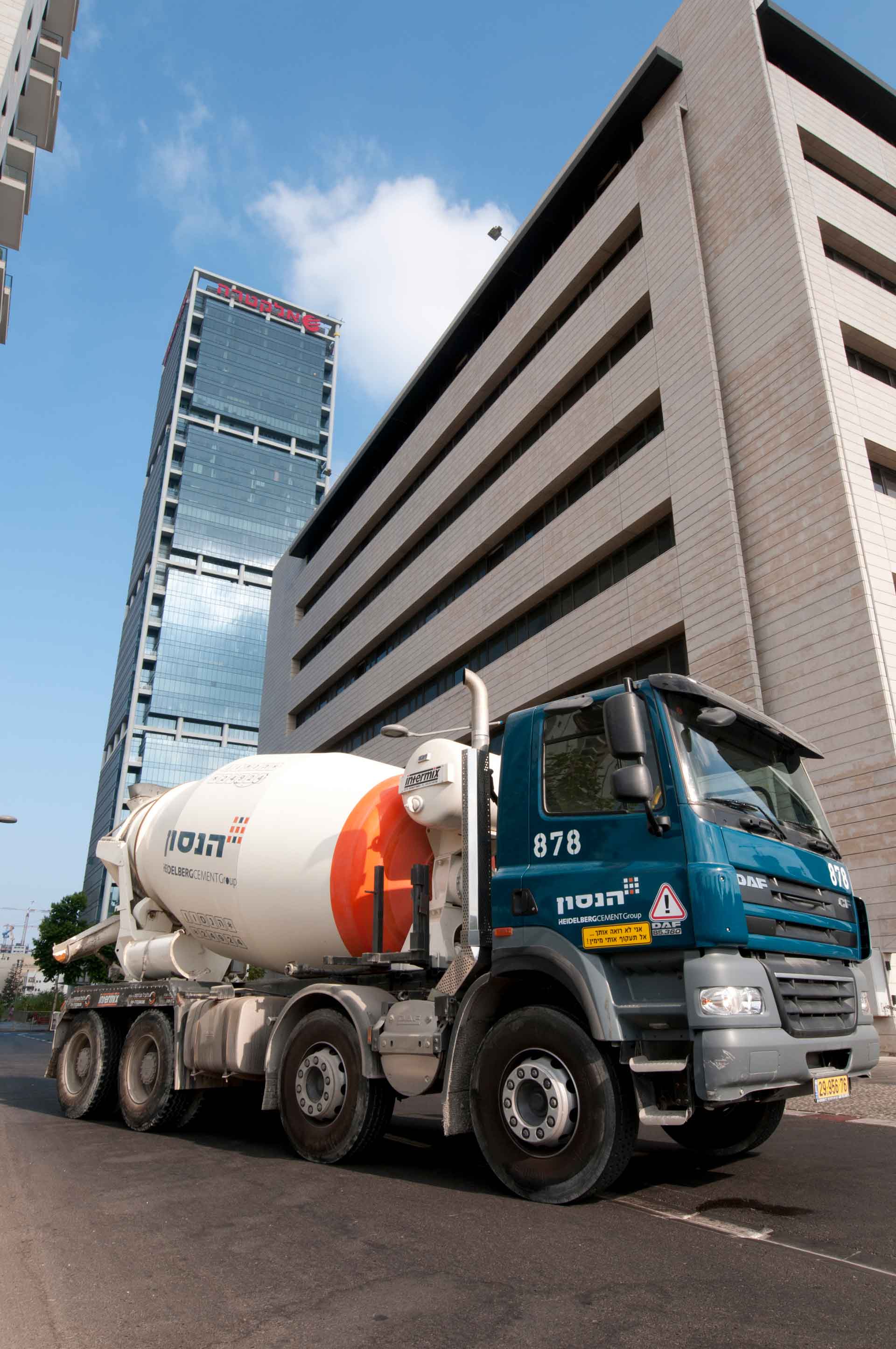 Truck mixer in front of a tower block with glass facade