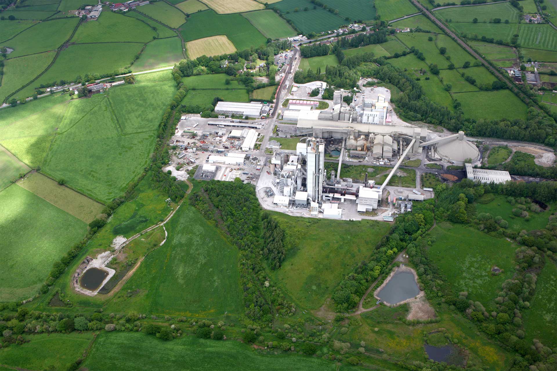 Aerial view of an industrial complex amid green fields, highlighting the contrast between industry and nature