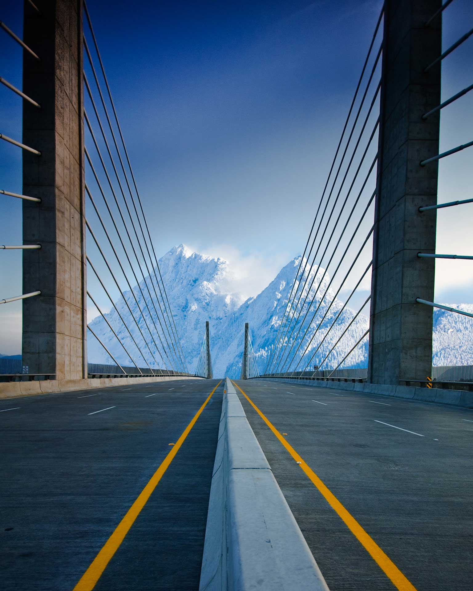 A modern suspension bridge with a central roadway flanked by tall, narrow towers supporting numerous cables. 