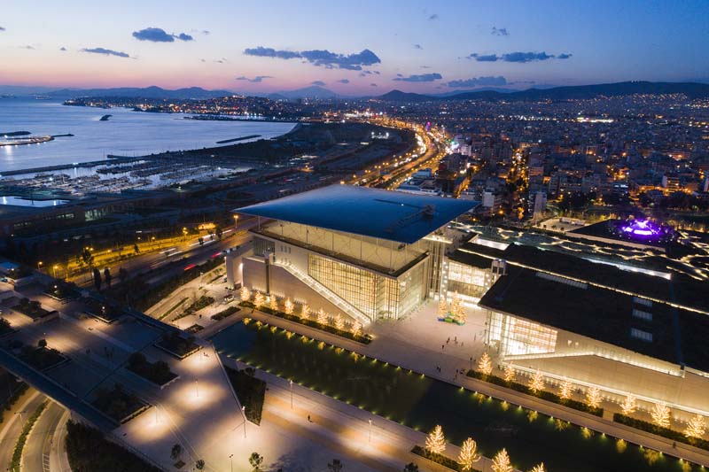 An aerial view of a large, illuminated building during twilight.