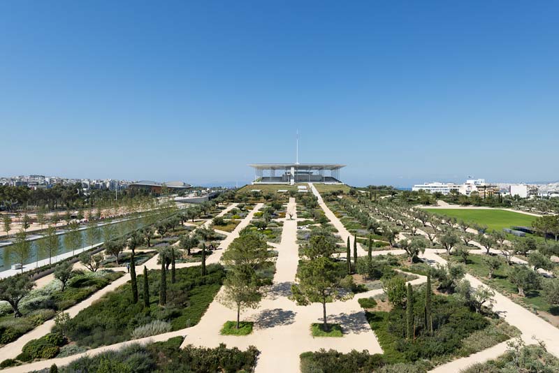 An aerial view of a formal garden with symmetrical layouts. There are neatly arranged hedges, pathways, and water features that create a patterned landscape design.