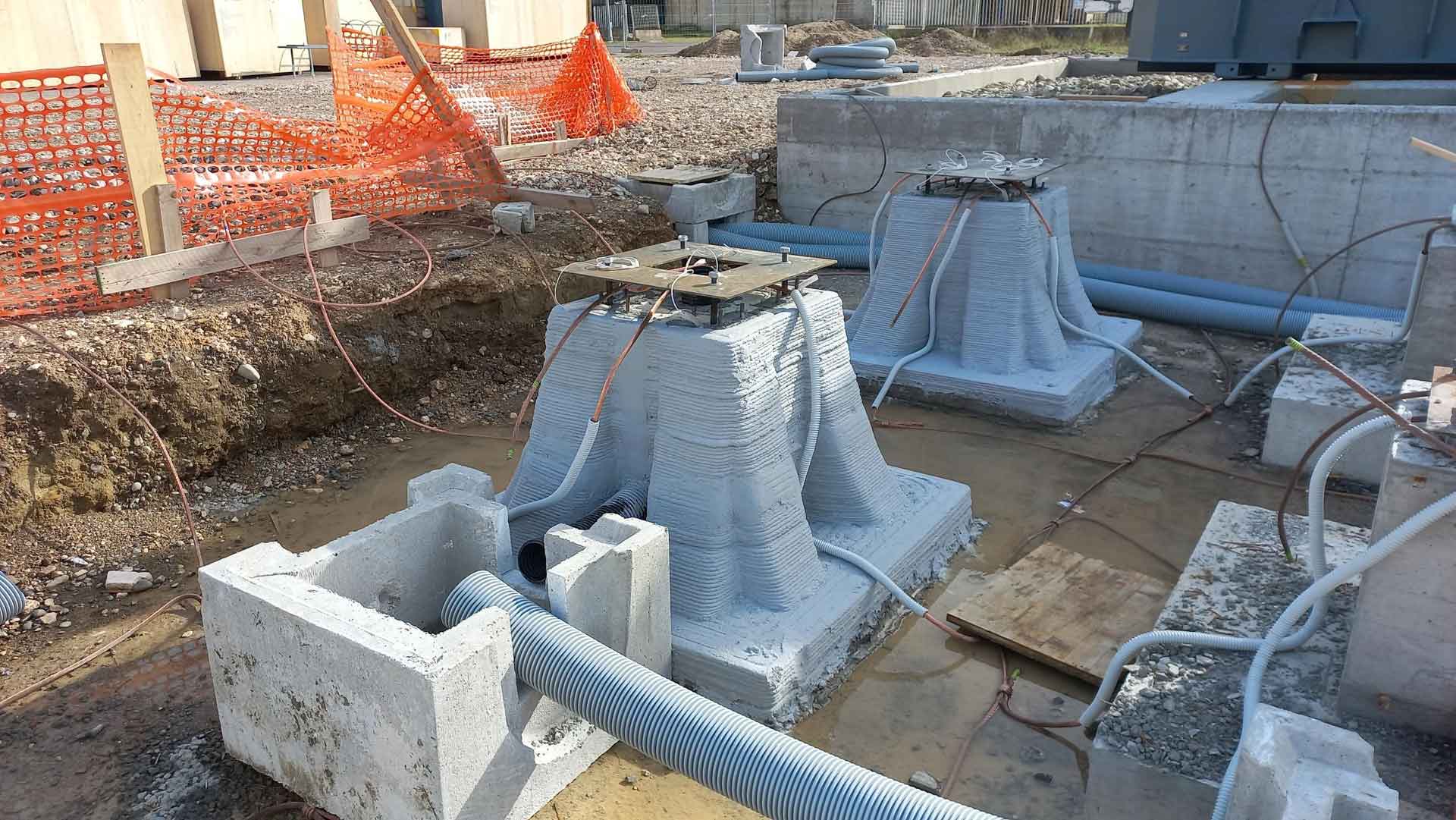 Several 3D-printed pillars at a construction site, showcasing the layered texture characteristic of 3D printing technology.