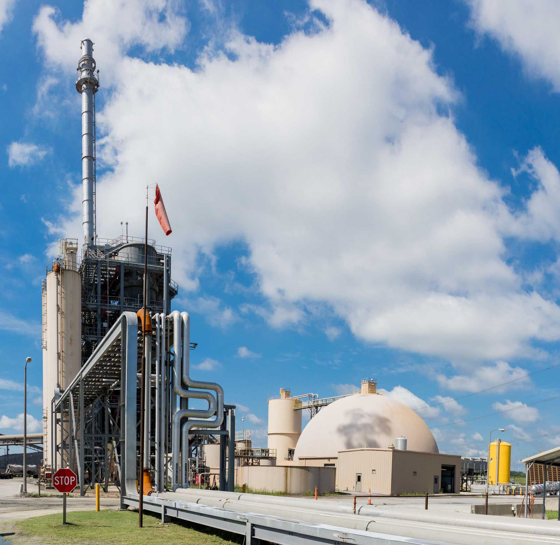 Facility with chimney in front of a blue sky with some white clouds