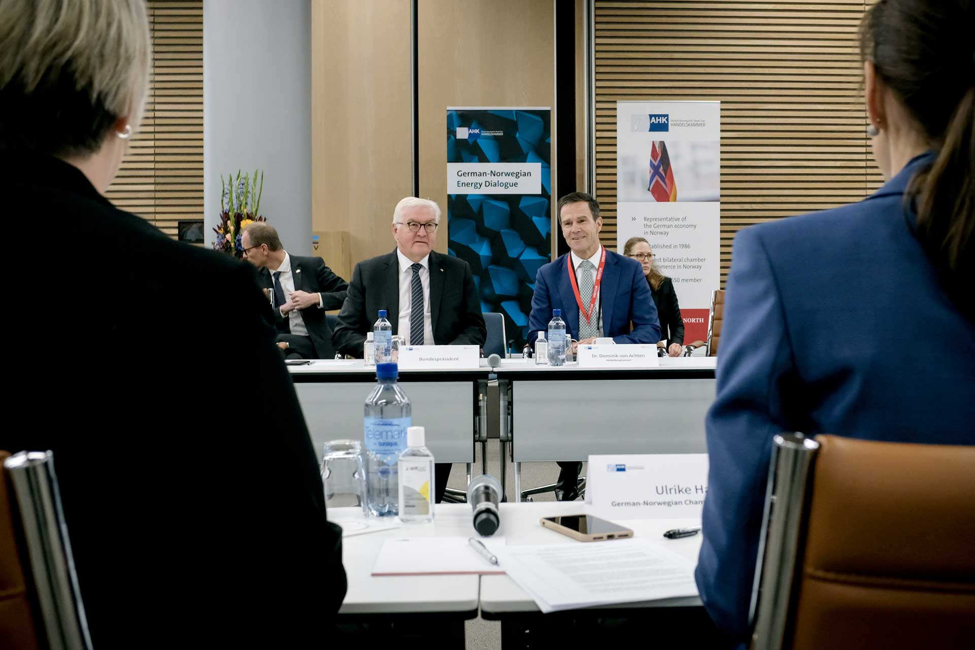 Federal President Steinmeier and Dominik von Achten at a conference, photographed from behind between two other participants