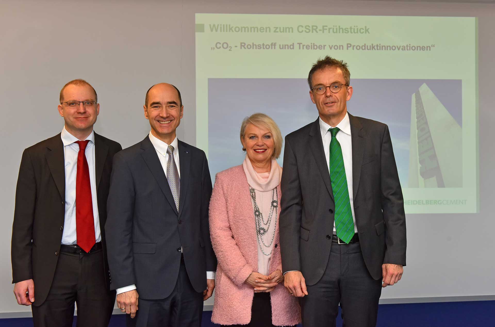 Four professionals standing before a presentation screen welcoming attendees to a CSR Breakfast event focused on CO₂ as an innovation driver.