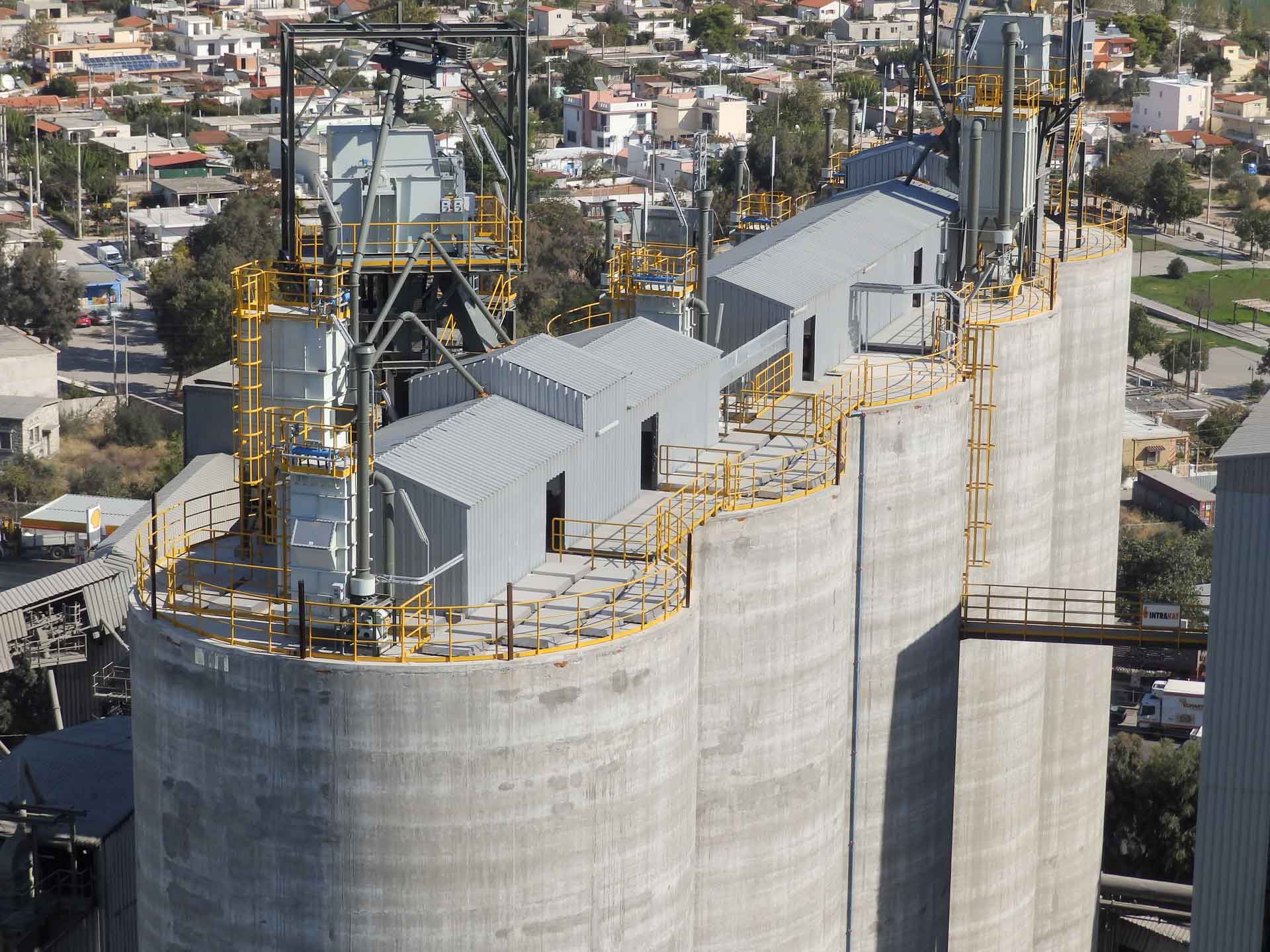 An aerial view of an industrial facility with several tall silos and connecting walkways.