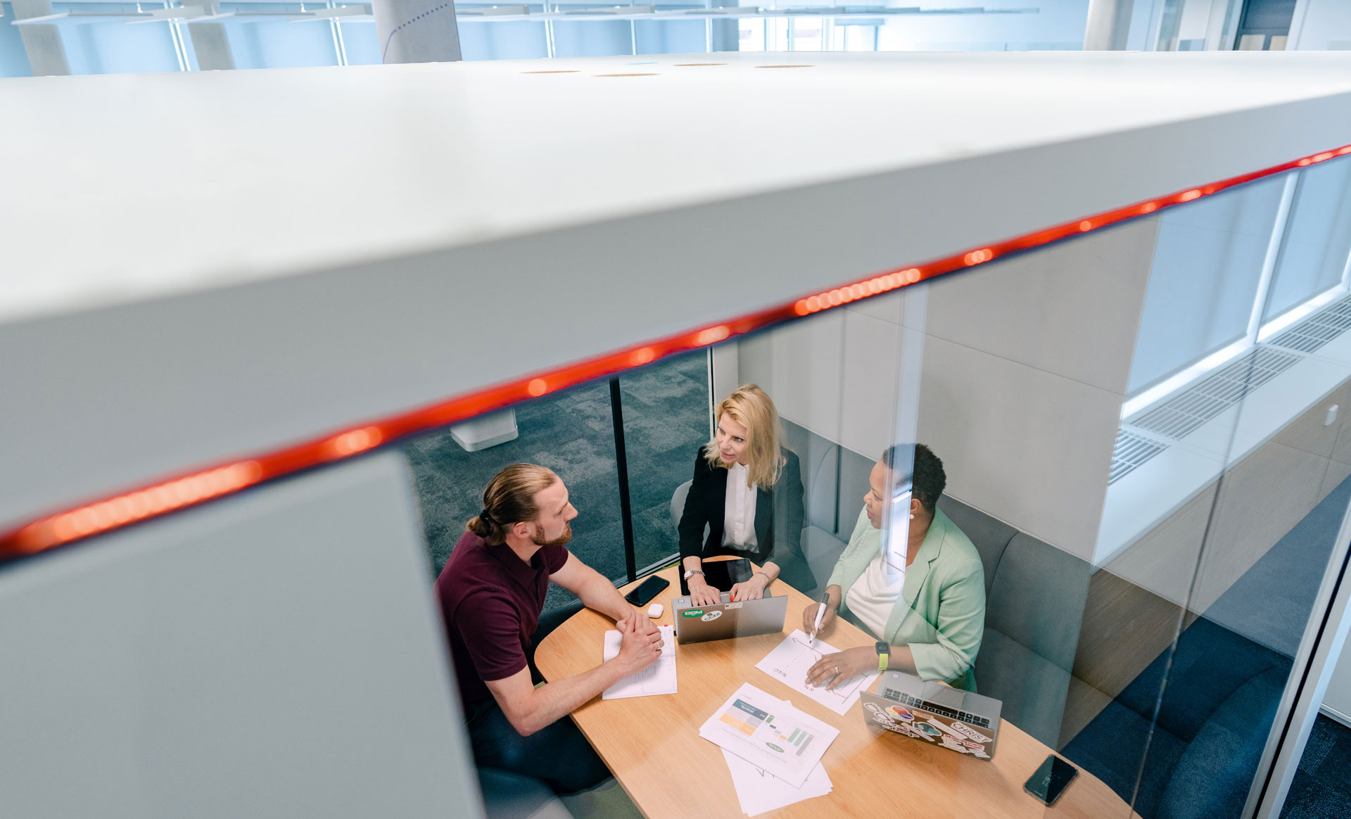 Three people sitting together at a meeting table, view from above