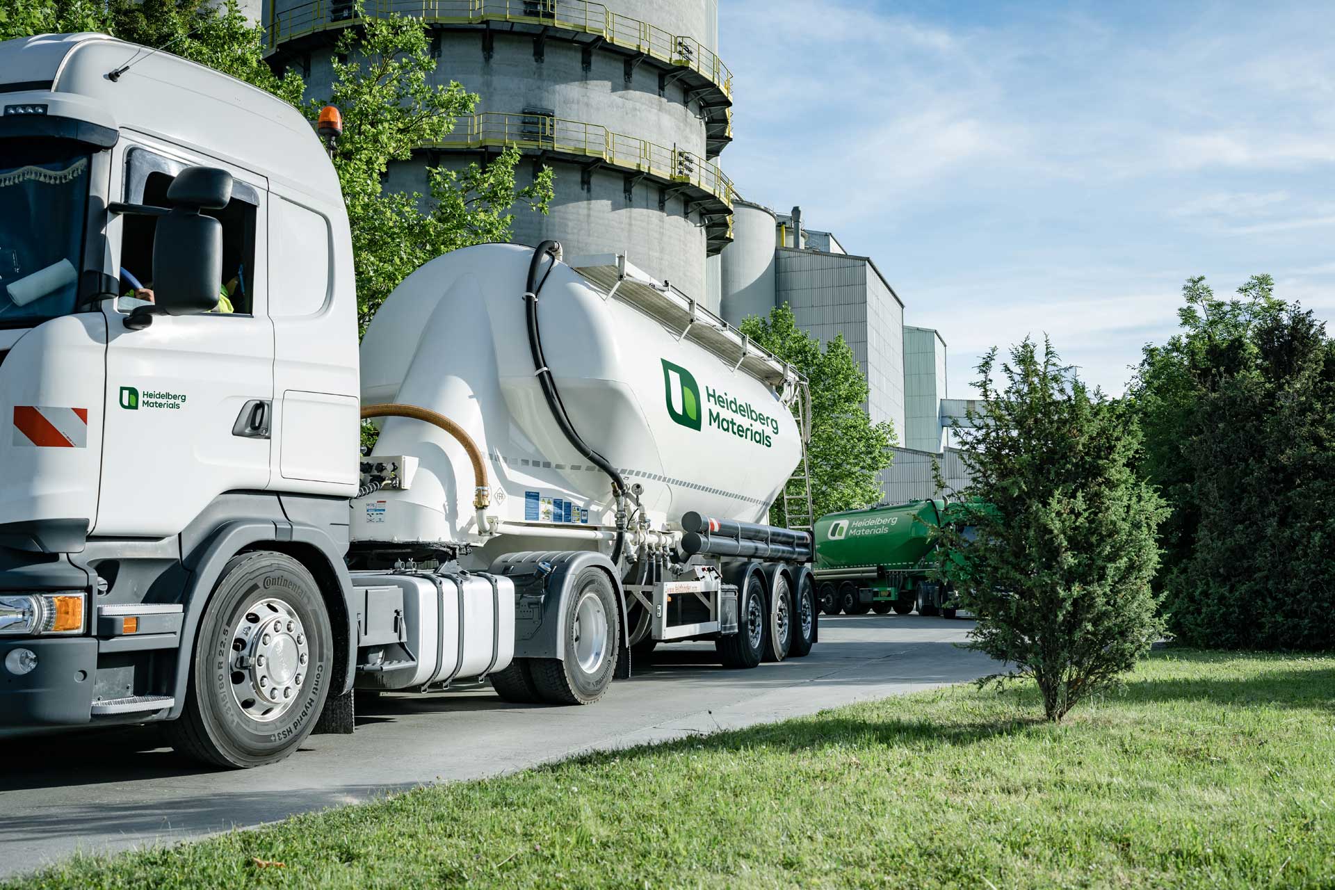 White silo truck in front of a cement plant