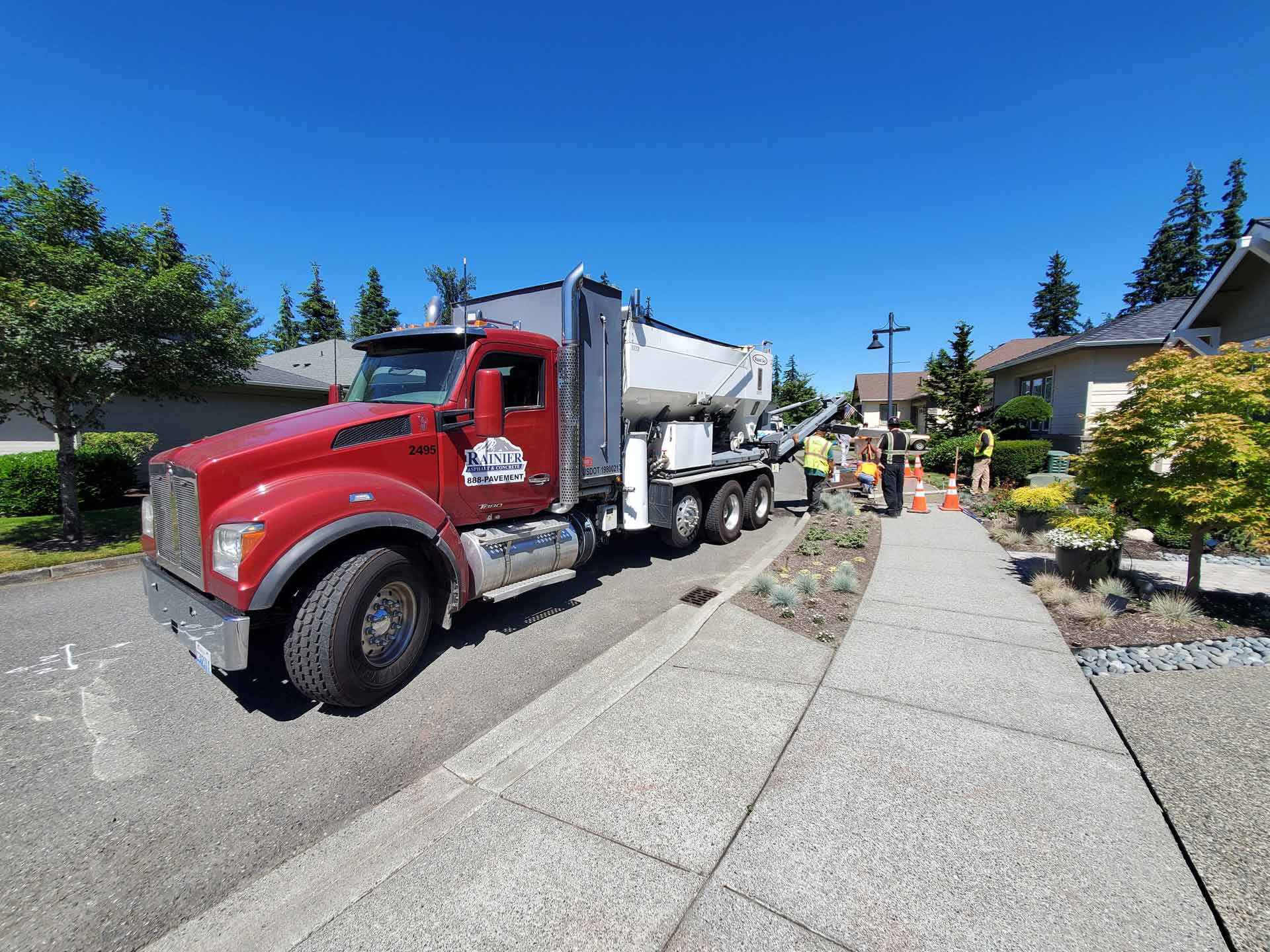 Red truck on a road, several people in high-visibility waistcoats standing next to it