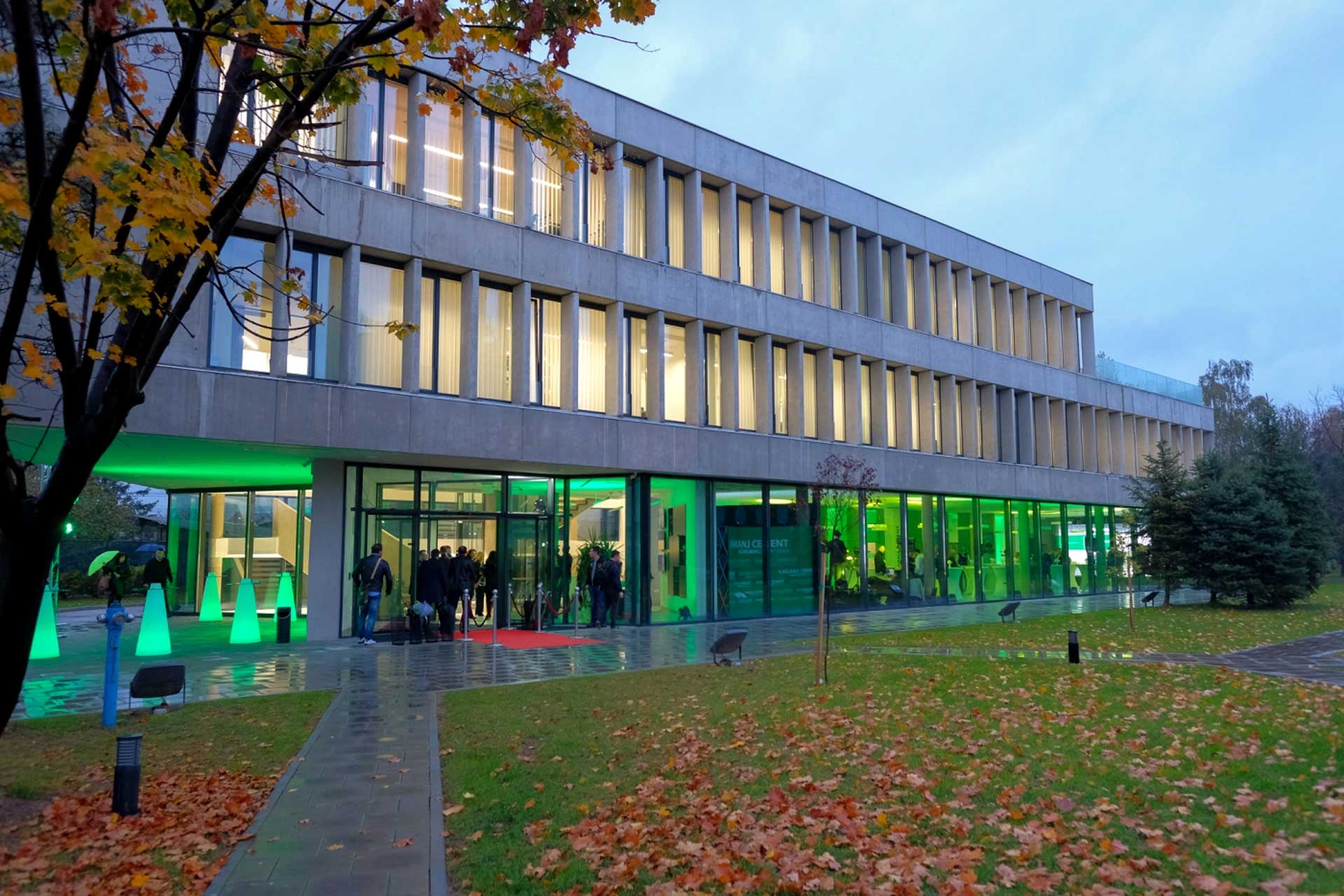 A modern office building with a glass facade. There are trees and a walkway in front of the building.