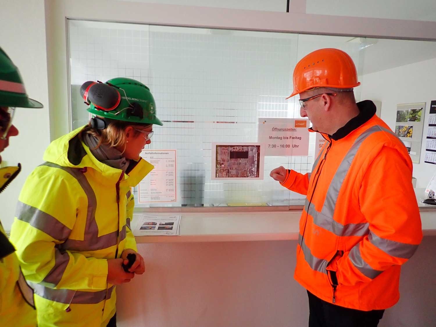 Man and woman wearing hard hats and protective clothing look at a plan together