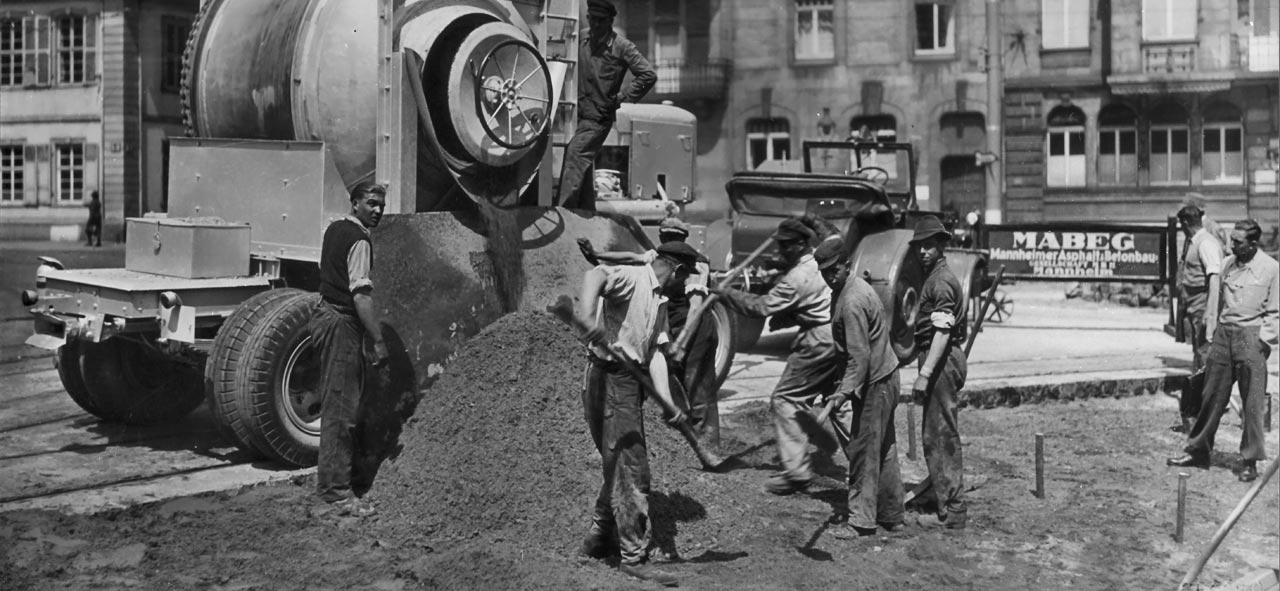 Historisches Foto einer Baustelle mit einigen Bauarbeitern und einem Fahrmischer, der gerade Beton liefert