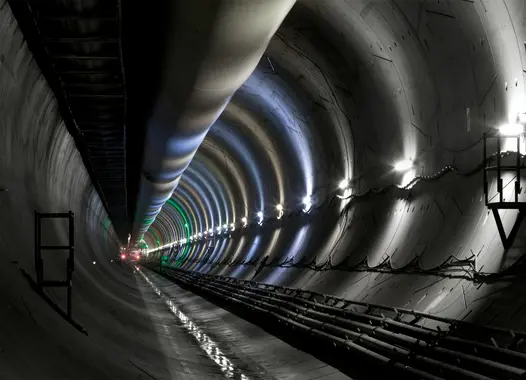 Innenansicht eines langen, beleuchteten Tunnels mit reflektierenden Wänden und Decke, zeigt Lichter und Konstruktionselemente