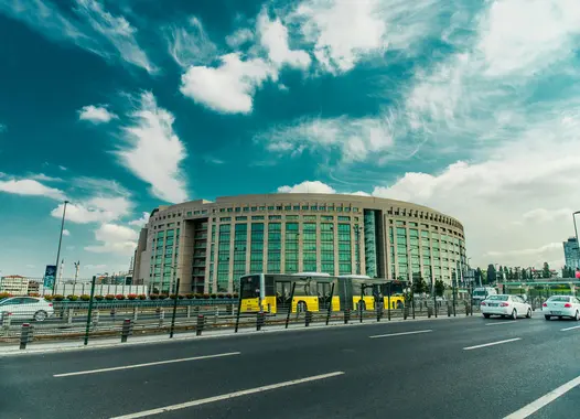 Ein modernes rundes Gebäude mit einer vorbeifahrenden gelben Straßenbahn unter bewölktem Himmel